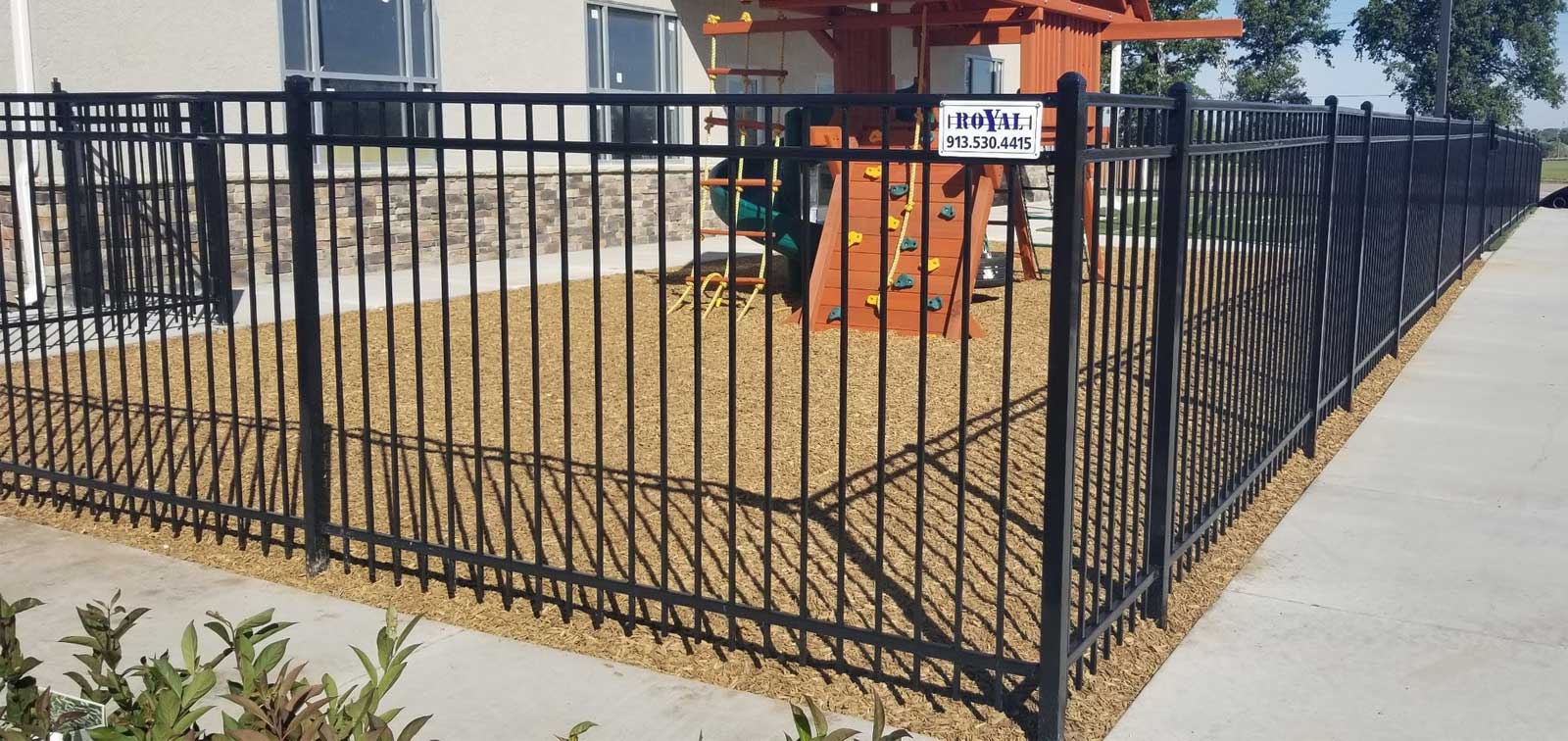 Five-foot black ornamental steel fence around a backyard play set