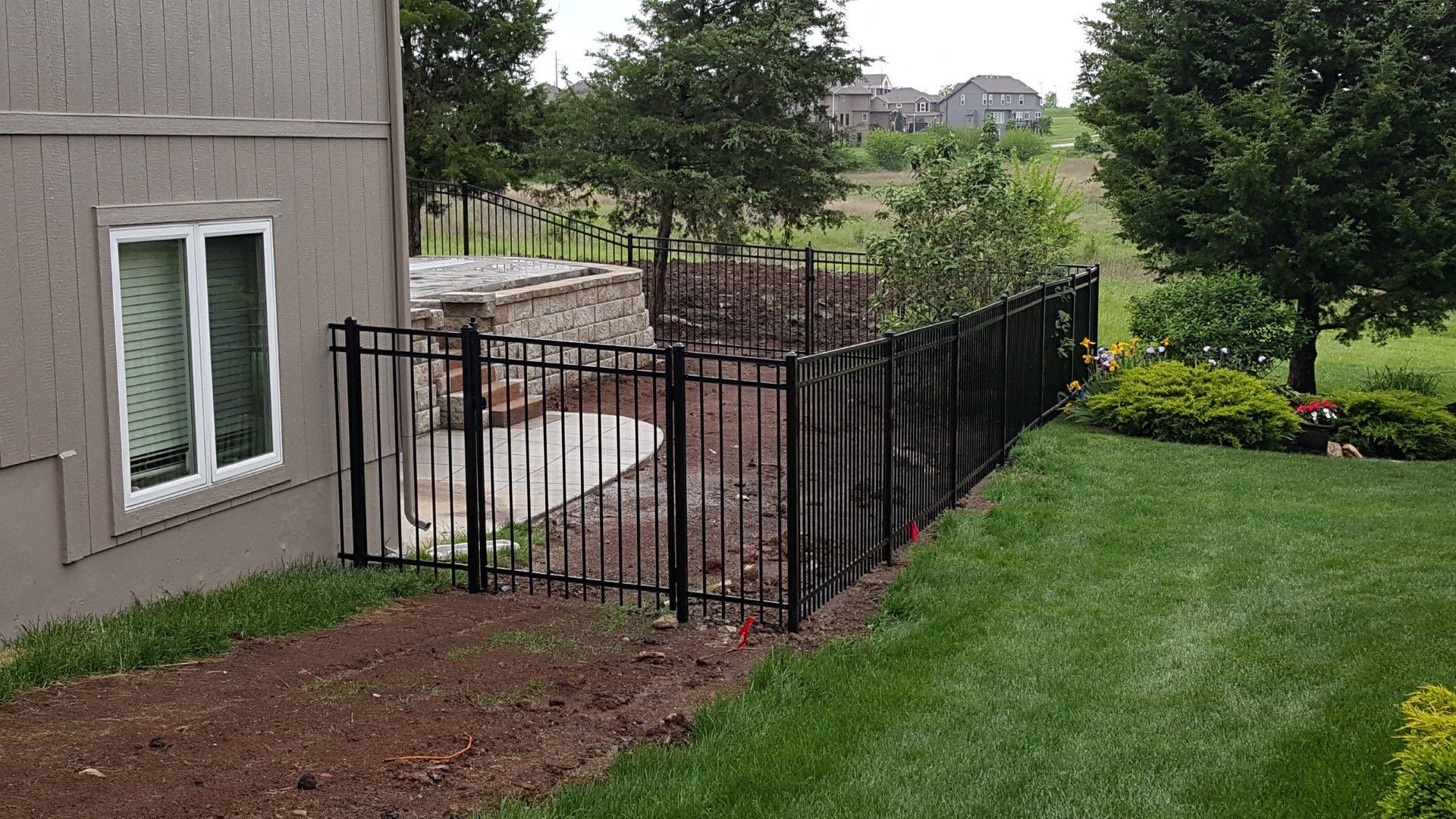 Black ornamental steel fence around a backyard patio