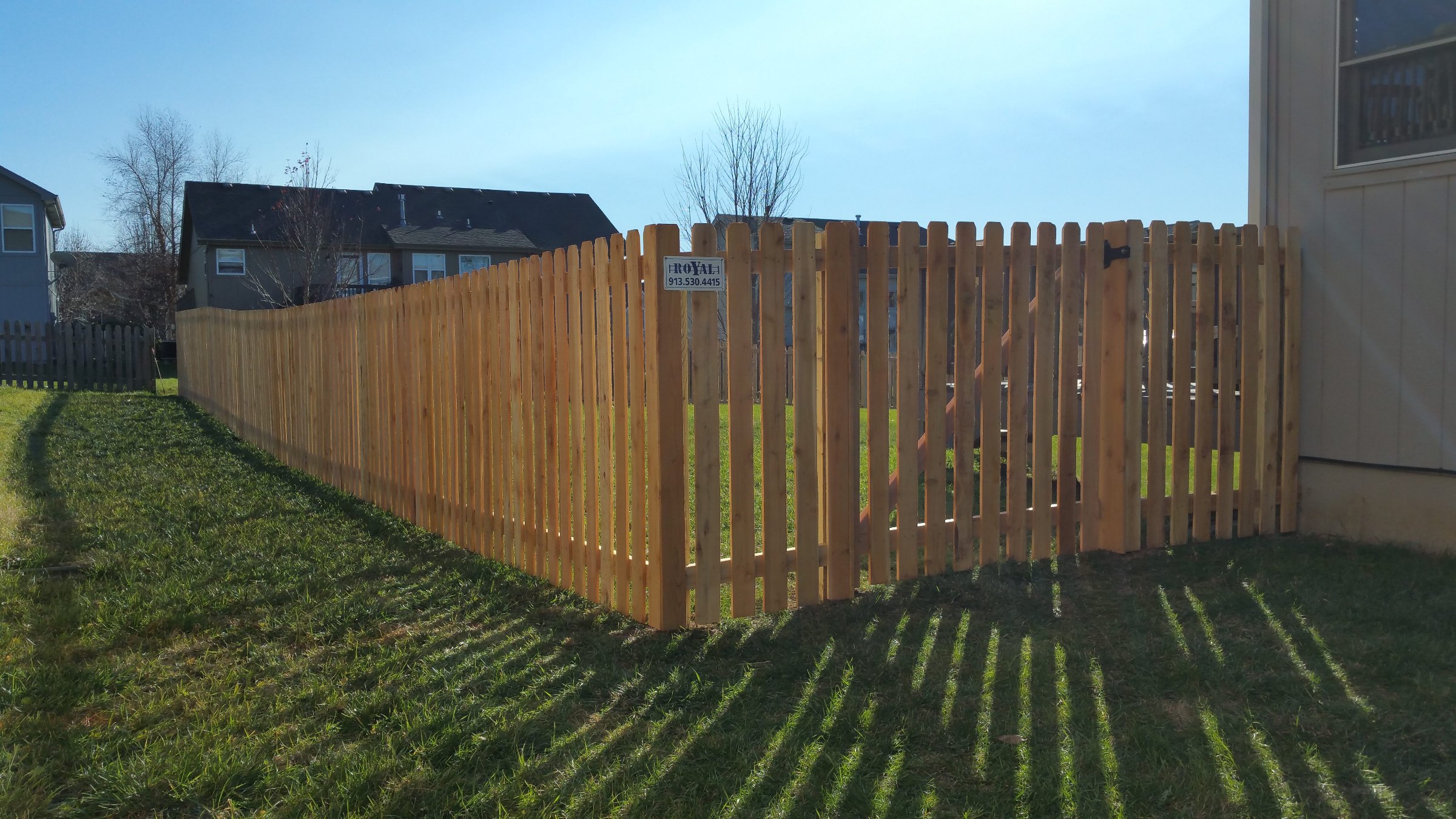 Spaced cedar picket fence and gate beside a house