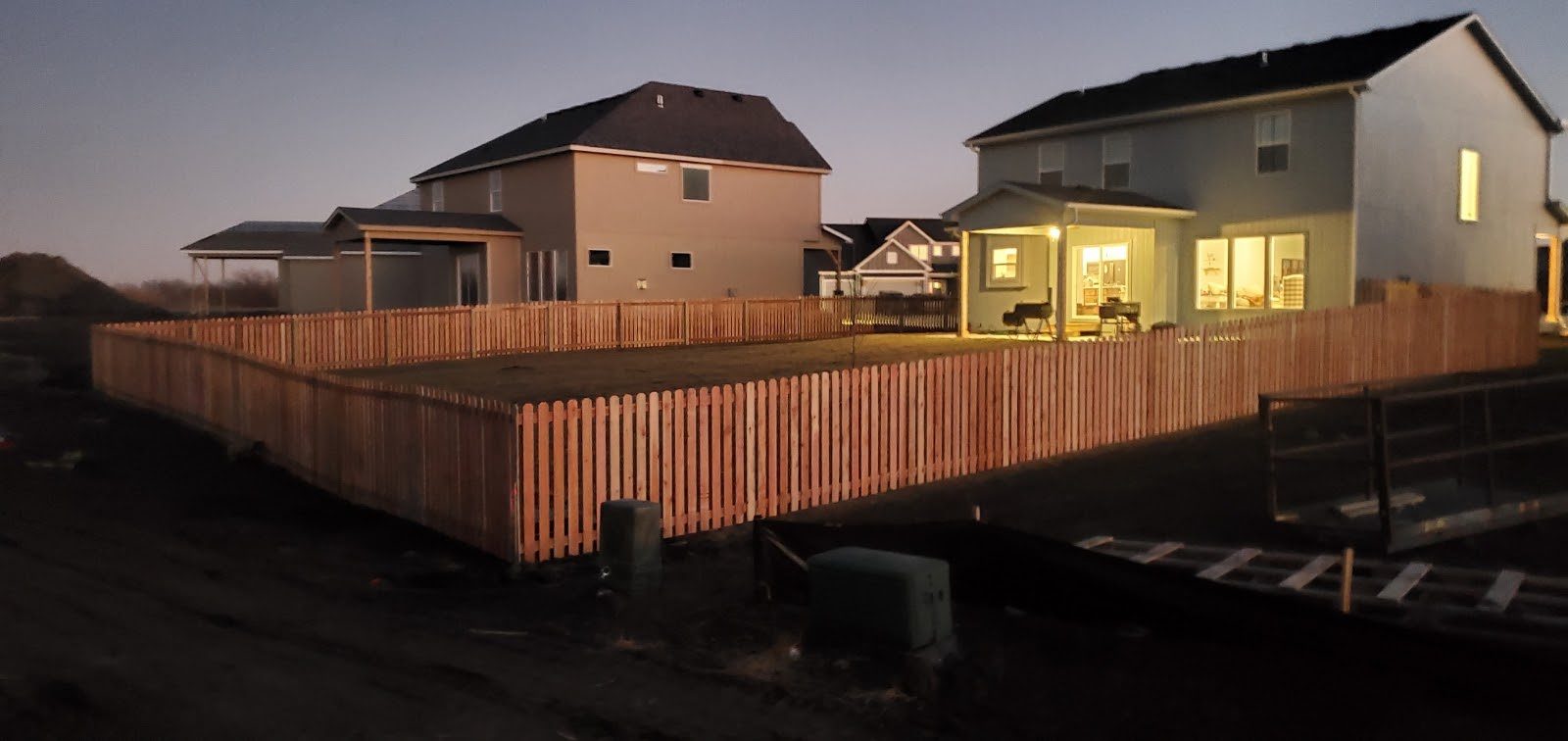 Five-foot spaced cedar fence around a new home at dusk