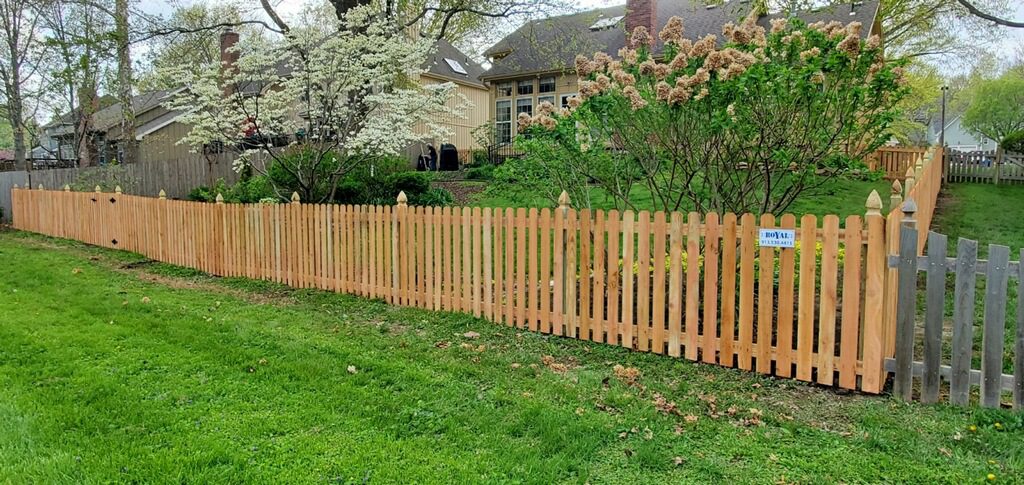 Spaced cedar picket fence with pointed post tops along a backyard