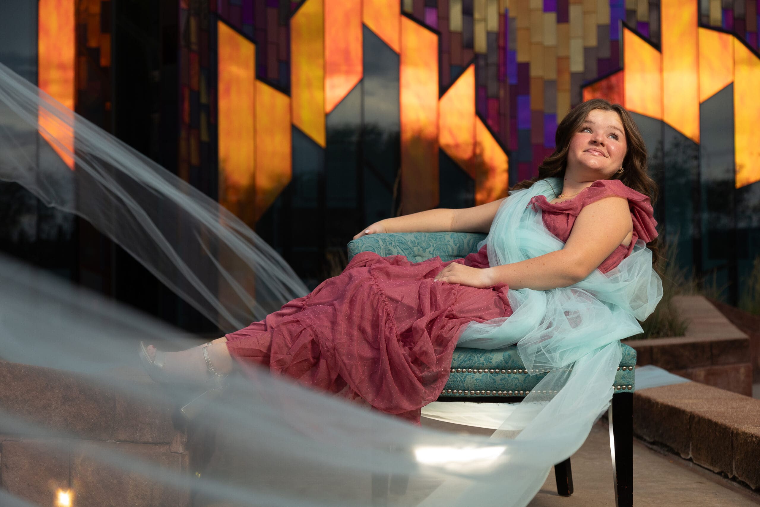 High school senior girl in a couture fine art portrait, styled in flowing fabrics and photographed against a colorful modern art wall by Gallery Portraiture Kansas City.