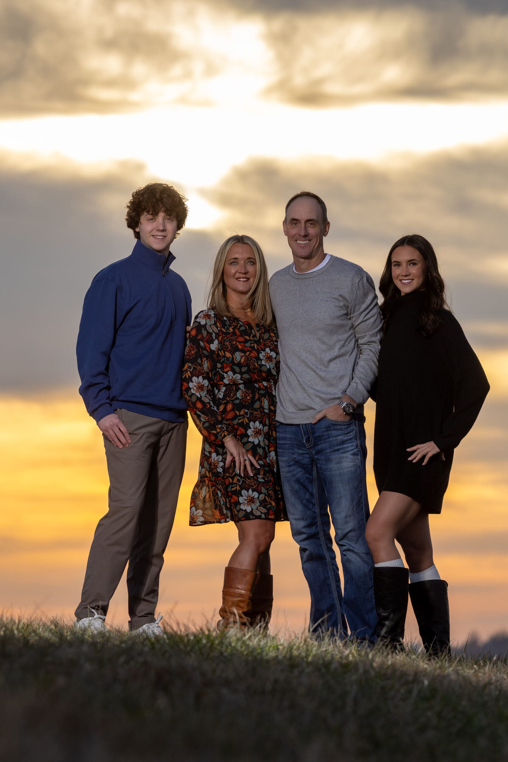 Family of four posing together during a sunset portrait session overlooking Downtown Kansas City near the Downtown Airport.
